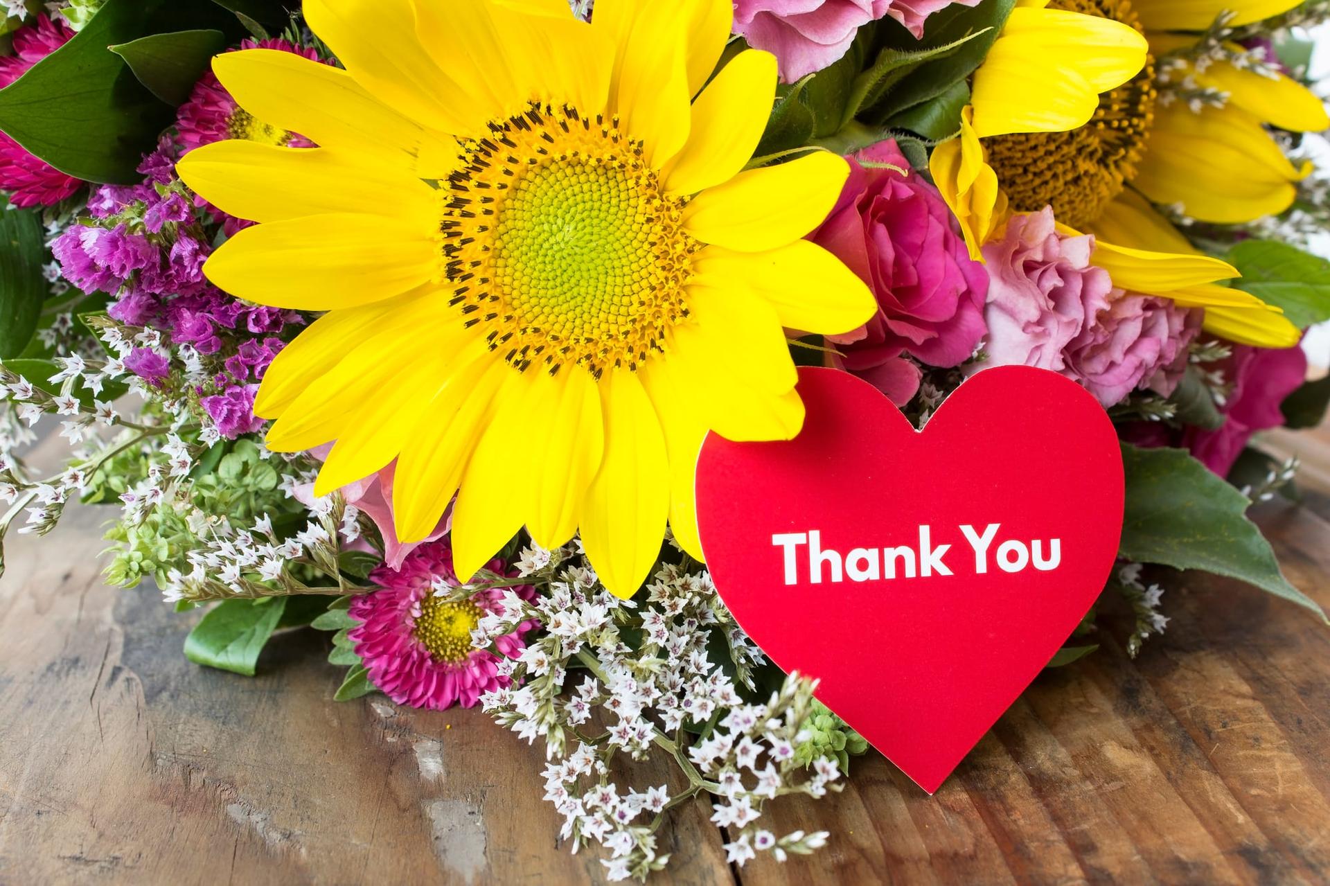 A thank-you card tucked into a bright summer bouquet