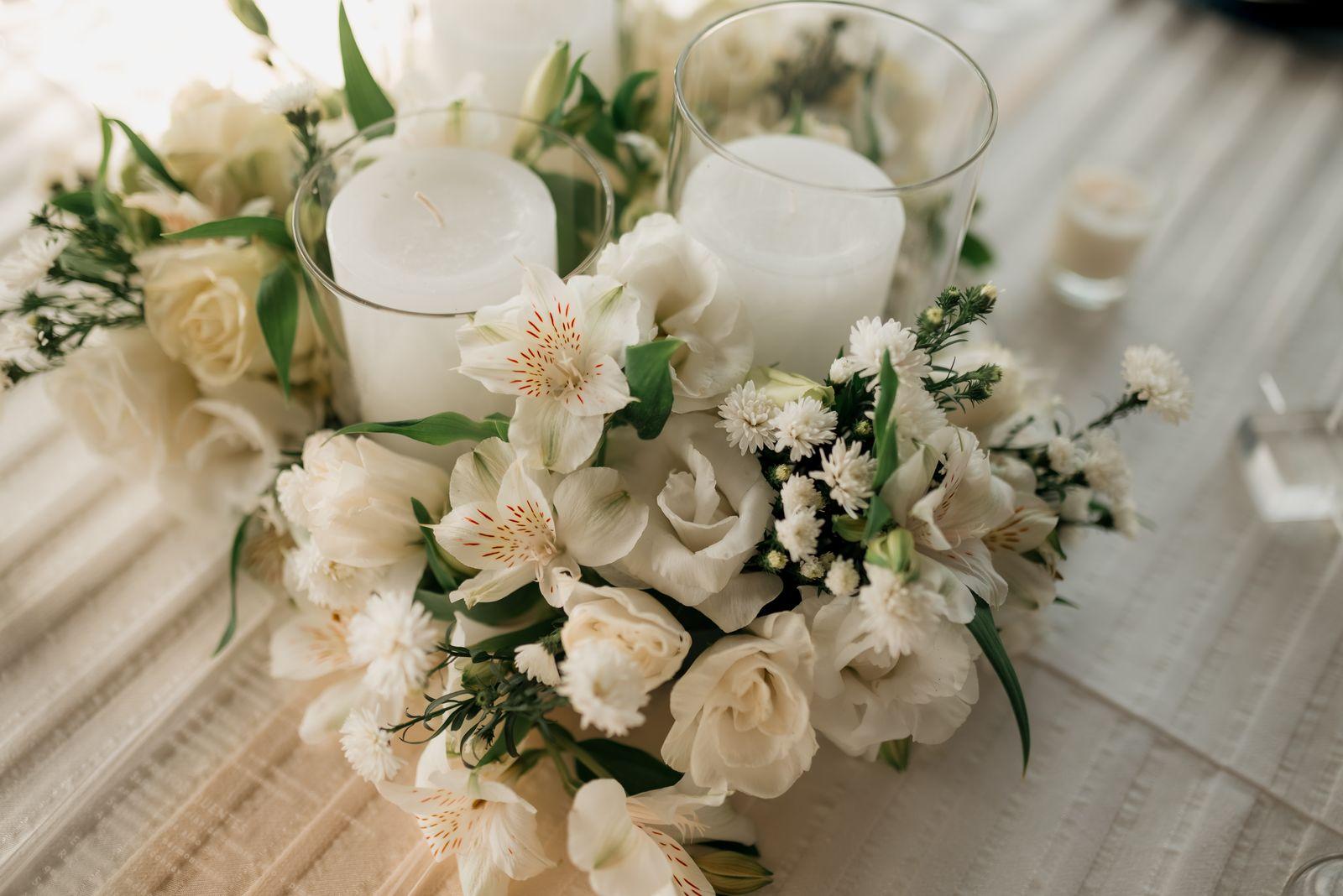 A white funeral flower arrangement beside lit candles