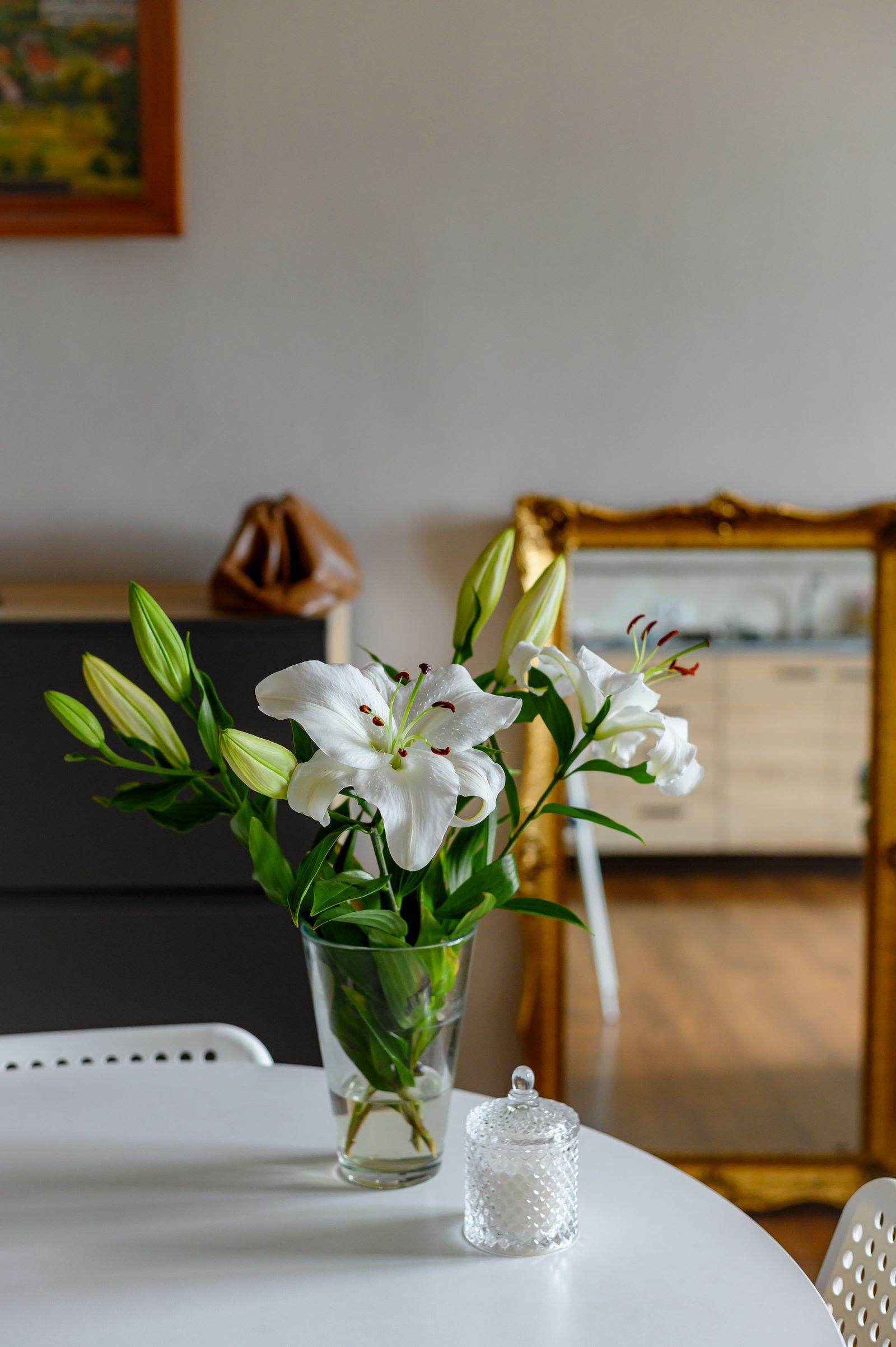 White oriental lilies with buds in a clear glass vase on a table