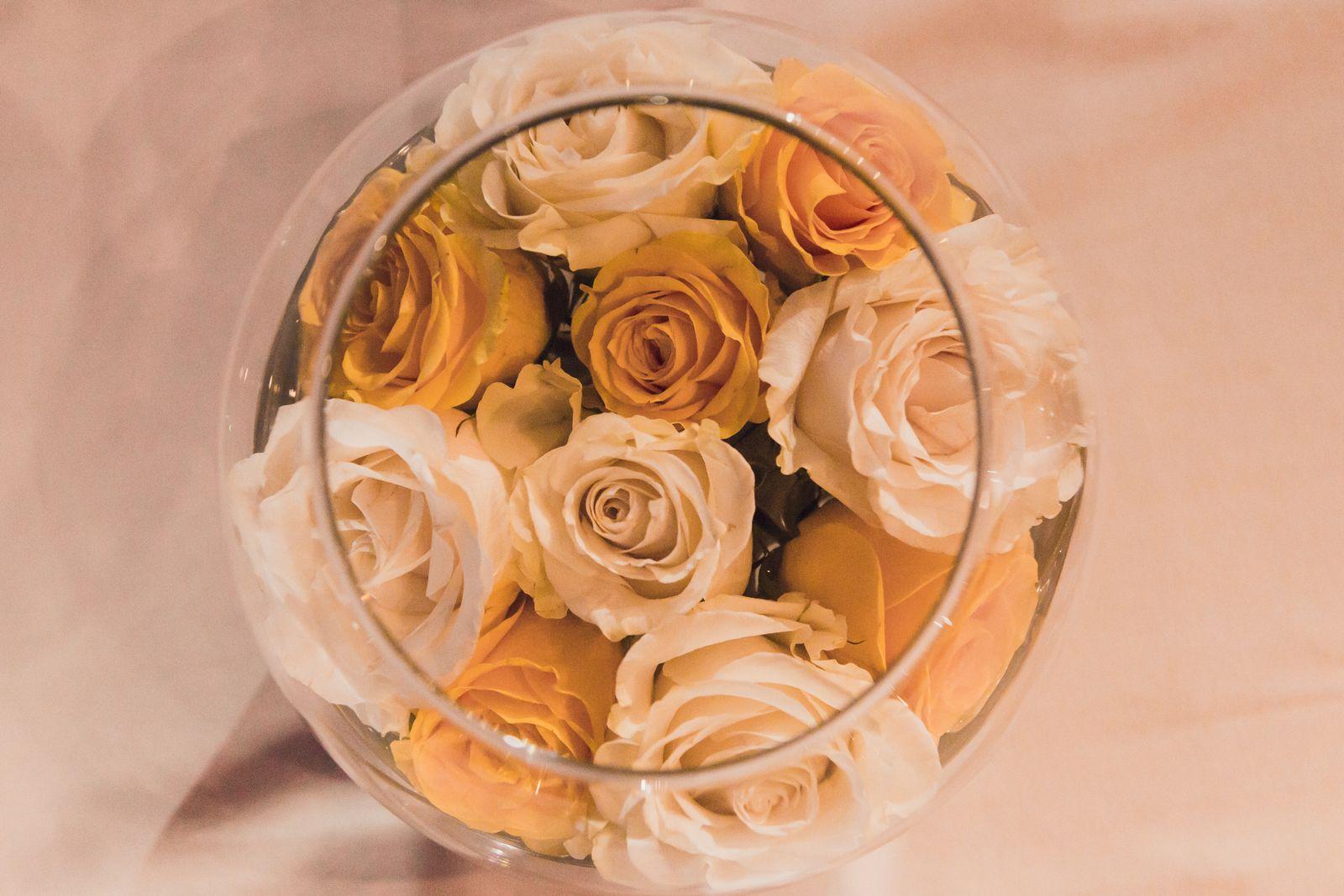 Cream and peach roses arranged in a round glass bowl, seen from above
