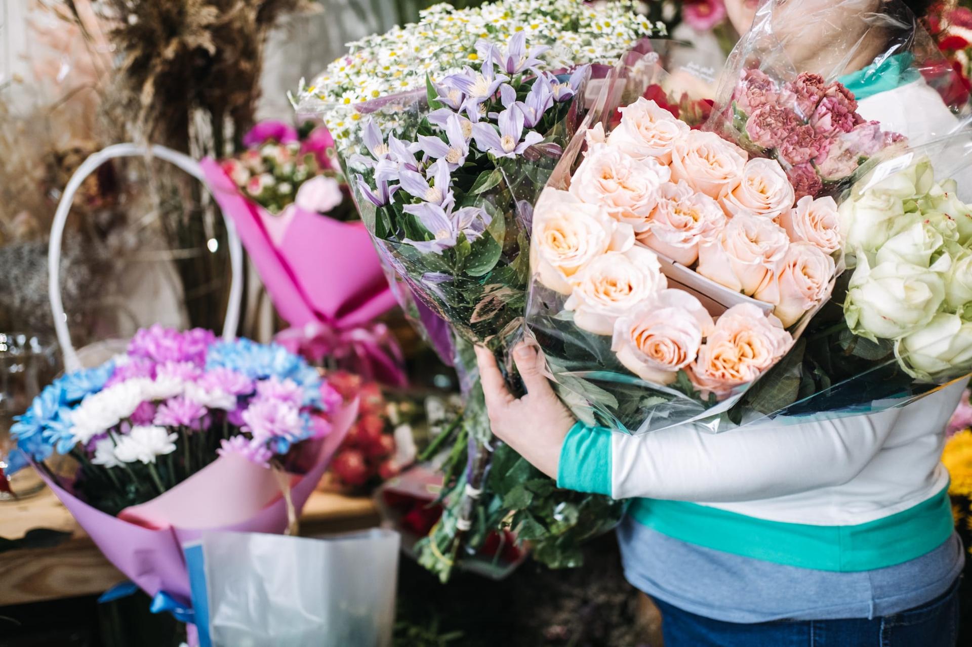 A florist holding several wrapped bouquets to choose from