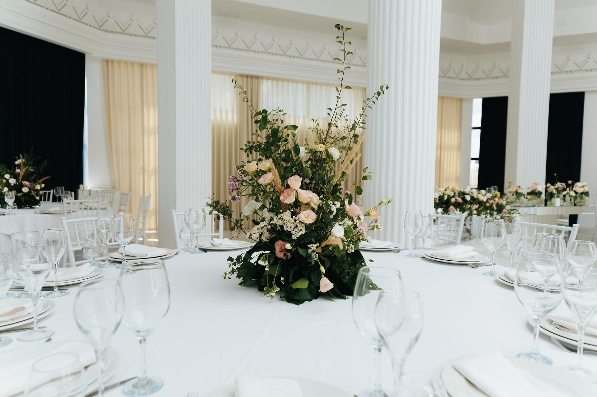 An elegant floral arrangement on a fully dressed wedding dining table