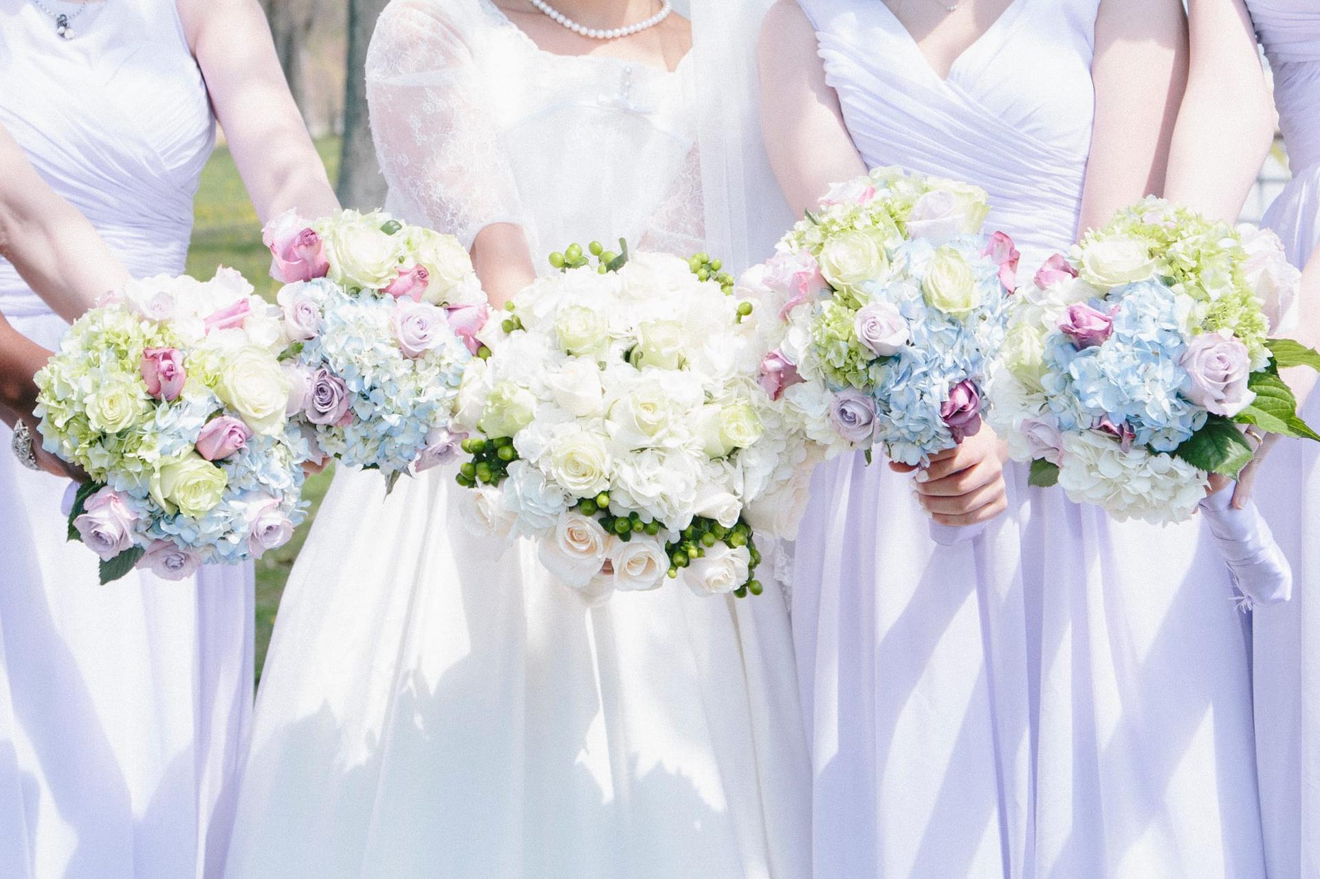 A bride and her bridesmaids standing side by side, each holding a bouquet