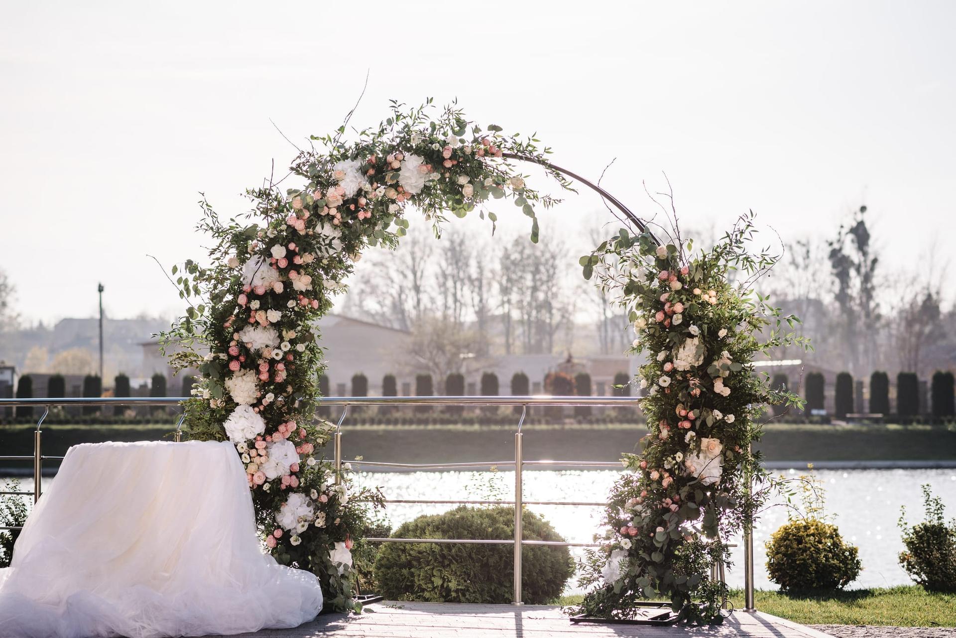 A wedding arch dressed with flowers and greenery at an outdoor venue