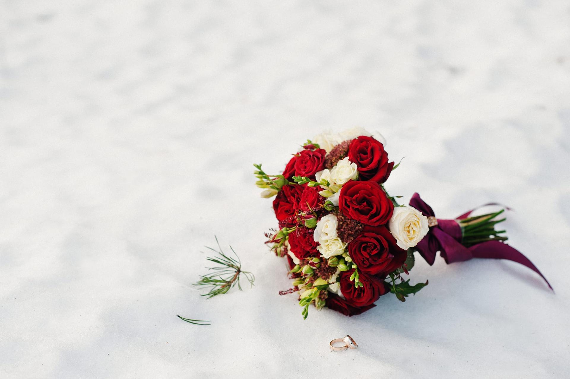 A wedding bouquet of white and red roses resting on snow